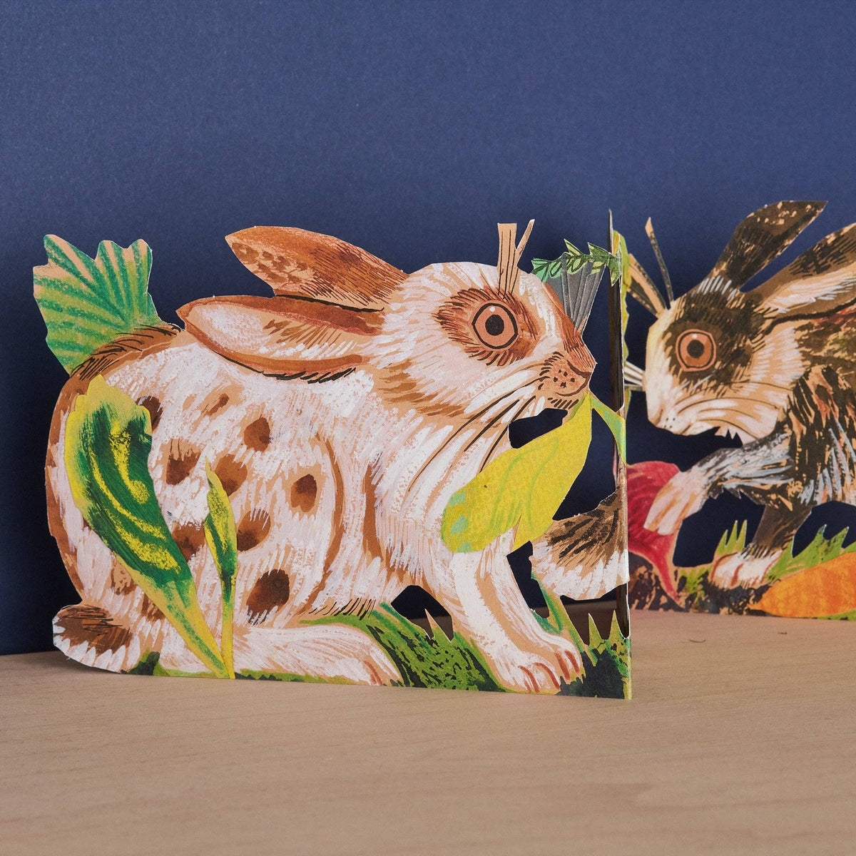 Close-up of the Mark Hearld Three Fold Rabbits accordion greeting card featuring illustrated rabbits among leafy woodland plants.