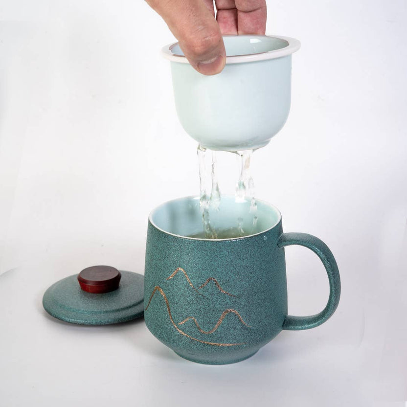 green mountain tea mug, porcelain tea mug with infuser, Urban Tokyo tea mug green, Japanese-style tea brewing mug, loose leaf tea porcelain cup, lidded infuser mug, minimalist green tea mug, modern Japanese home goods, gift for tea drinkers, mountain design mug, cozy kitchen gifts, ceramic tea mug with lid, Rogue & Rye cozy rituals collection, elegant tea accessories, woman-owned brand gift ideas.