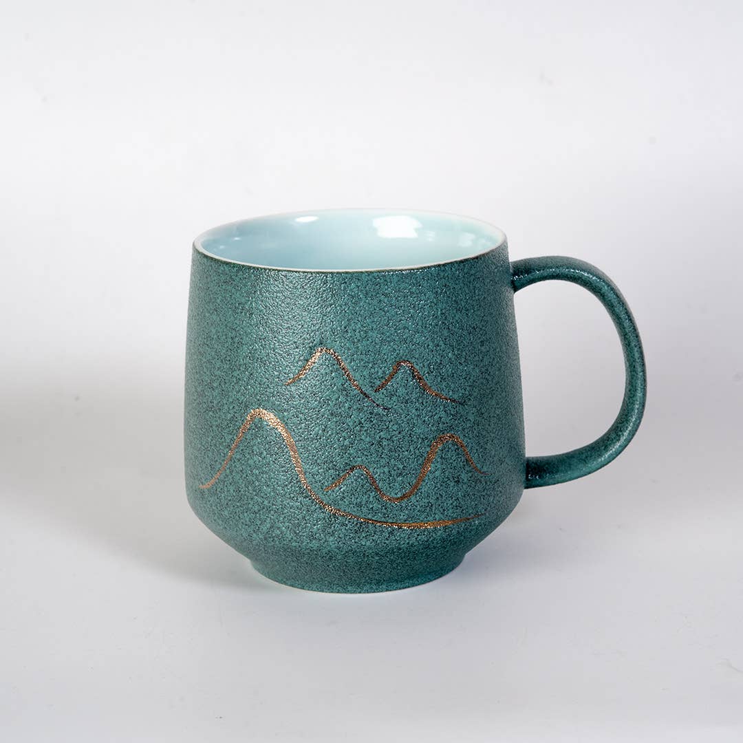 green mountain tea mug, porcelain tea mug with infuser, Urban Tokyo tea mug green, Japanese-style tea brewing mug, loose leaf tea porcelain cup, lidded infuser mug, minimalist green tea mug, modern Japanese home goods, gift for tea drinkers, mountain design mug, cozy kitchen gifts, ceramic tea mug with lid, Rogue & Rye cozy rituals collection, elegant tea accessories, woman-owned brand gift ideas.