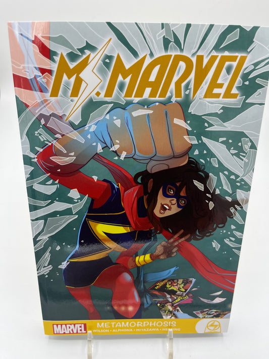 Cover of Ms. Marvel: Metamorphosis featuring Kamala Khan punching through shattered glass while wearing her Ms. Marvel costume.