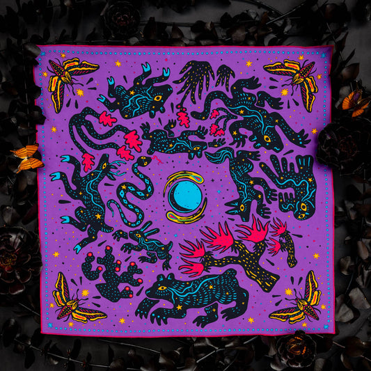 Pine Bones Electric Desert Parade bandana featuring coyotes, ravens, snakes, lizards, desert plants, and a bright blue moon arranged in a vibrant Southwestern-inspired design.