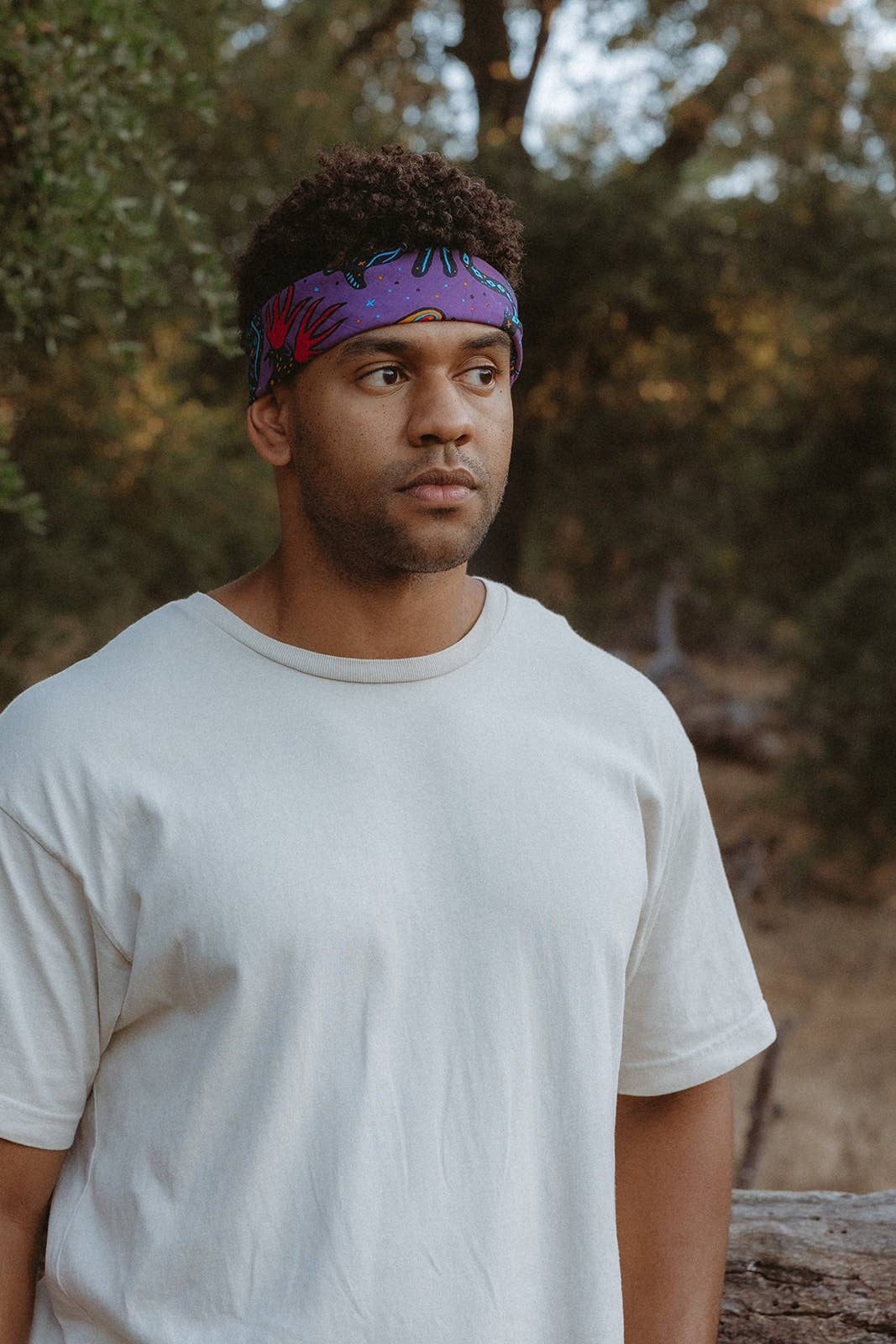 Model wearing the Pine Bones Electric Desert Parade bandana as a headband, showcasing the vibrant purple desert wildlife design.