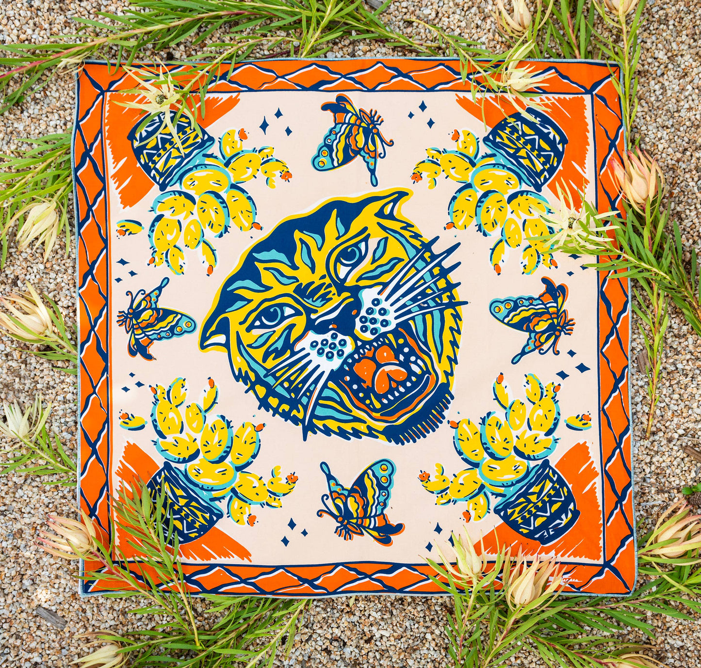 The Desert Sun Bandana by Bandits Bandanas features original artwork by Michael Matheson (Metal Teepee) and is made from Fair Trade Certified, 100% organic cotton. Soft, breathable, and versatile, this 21" × 21" bandana is perfect for hair, neck, or bag styling. Each purchase gives back, with 10% of proceeds supporting the International Rescue Committee, making it a meaningful, artist-driven accessory designed to be lived in.