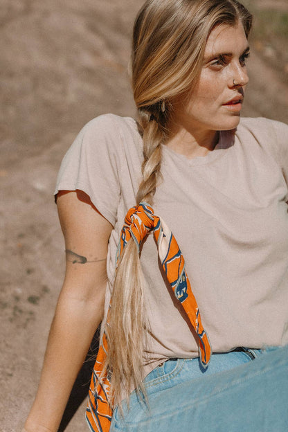 The Desert Sun Bandana by Bandits Bandanas features original artwork by Michael Matheson (Metal Teepee) and is made from Fair Trade Certified, 100% organic cotton. Soft, breathable, and versatile, this 21" × 21" bandana is perfect for hair, neck, or bag styling. Each purchase gives back, with 10% of proceeds supporting the International Rescue Committee, making it a meaningful, artist-driven accessory designed to be lived in.