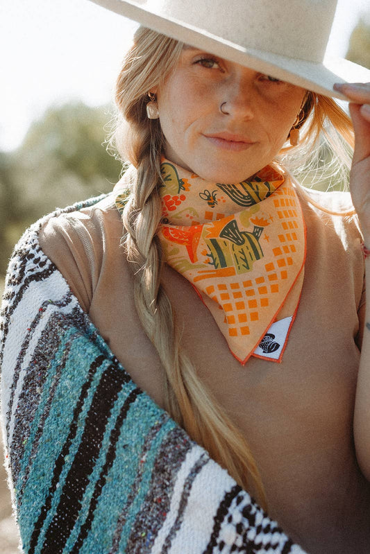The Prickly Pollinators Bandana by Bandits Bandanas features original artwork by Zaine Vaun and celebrates the desert as a vibrant, living ecosystem. Made from GOTS-certified organic cotton and handcrafted in a Fair Trade Certified facility, this ultra-soft 21" × 21" bandana is perfect for styling in your hair, around your neck, or tied to a favorite bag. Each purchase gives back, with 10% of proceeds supporting Big Bend Conservation Alliance.