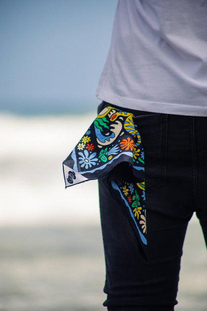 The Tropic Like It’s Hot Bandana by Bandits Bandanas features original artwork by Joshua Noom and is crafted from GOTS-certified, Fair Trade Certified organic cotton. Soft, breathable, and easy to style, this 21" × 21" bandana is perfect for everyday wear—at the neck, in the hair, or tied to a favorite bag. Each purchase gives back, with 10% of proceeds supporting American Red Cross Hurricane Relief, making it a vibrant, artist-driven accessory with meaningful impact.