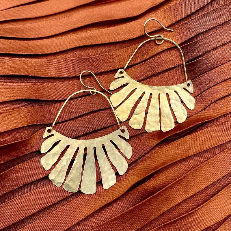 The Freya Earrings by Fluff Hardware are handcrafted gold statement earrings featuring hammered raw brass pendants suspended from hypoallergenic 14k gold filled ear wires. Designed to move beautifully with the wearer, these small-batch earrings offer a warm, luminous finish that works just as well for everyday wear as for special occasions—an artful, versatile gift for lovers of modern, handmade jewelry.