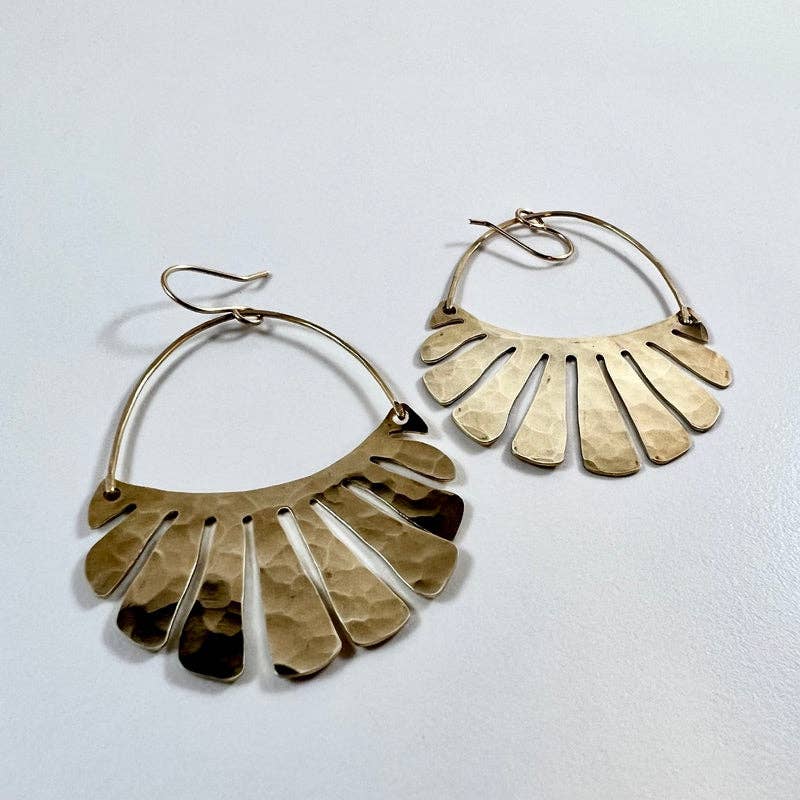 The Freya Earrings by Fluff Hardware are handcrafted gold statement earrings featuring hammered raw brass pendants suspended from hypoallergenic 14k gold filled ear wires. Designed to move beautifully with the wearer, these small-batch earrings offer a warm, luminous finish that works just as well for everyday wear as for special occasions—an artful, versatile gift for lovers of modern, handmade jewelry.