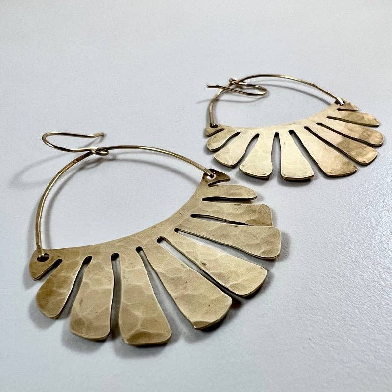 The Freya Earrings by Fluff Hardware are handcrafted gold statement earrings featuring hammered raw brass pendants suspended from hypoallergenic 14k gold filled ear wires. Designed to move beautifully with the wearer, these small-batch earrings offer a warm, luminous finish that works just as well for everyday wear as for special occasions—an artful, versatile gift for lovers of modern, handmade jewelry.