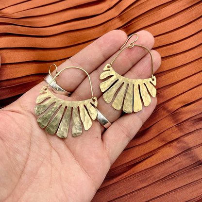 The Freya Earrings by Fluff Hardware are handcrafted gold statement earrings featuring hammered raw brass pendants suspended from hypoallergenic 14k gold filled ear wires. Designed to move beautifully with the wearer, these small-batch earrings offer a warm, luminous finish that works just as well for everyday wear as for special occasions—an artful, versatile gift for lovers of modern, handmade jewelry.