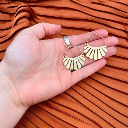 The Freya Earrings by Fluff Hardware are handcrafted gold statement earrings featuring hammered raw brass pendants suspended from hypoallergenic 14k gold filled ear wires. Designed to move beautifully with the wearer, these small-batch earrings offer a warm, luminous finish that works just as well for everyday wear as for special occasions—an artful, versatile gift for lovers of modern, handmade jewelry.