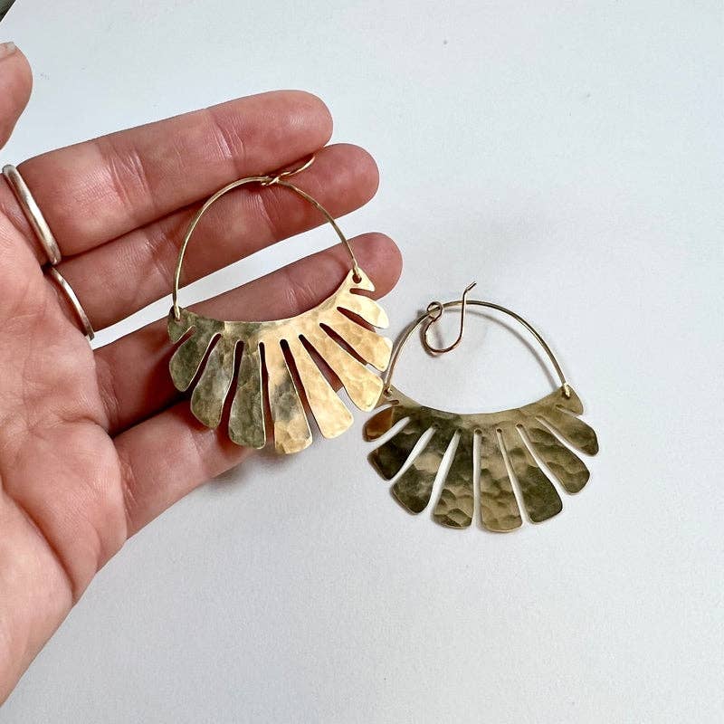 The Freya Earrings by Fluff Hardware are handcrafted gold statement earrings featuring hammered raw brass pendants suspended from hypoallergenic 14k gold filled ear wires. Designed to move beautifully with the wearer, these small-batch earrings offer a warm, luminous finish that works just as well for everyday wear as for special occasions—an artful, versatile gift for lovers of modern, handmade jewelry.
