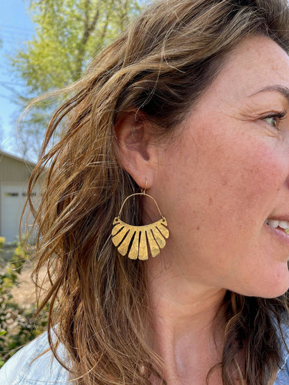 The Freya Earrings by Fluff Hardware are handcrafted gold statement earrings featuring hammered raw brass pendants suspended from hypoallergenic 14k gold filled ear wires. Designed to move beautifully with the wearer, these small-batch earrings offer a warm, luminous finish that works just as well for everyday wear as for special occasions—an artful, versatile gift for lovers of modern, handmade jewelry.