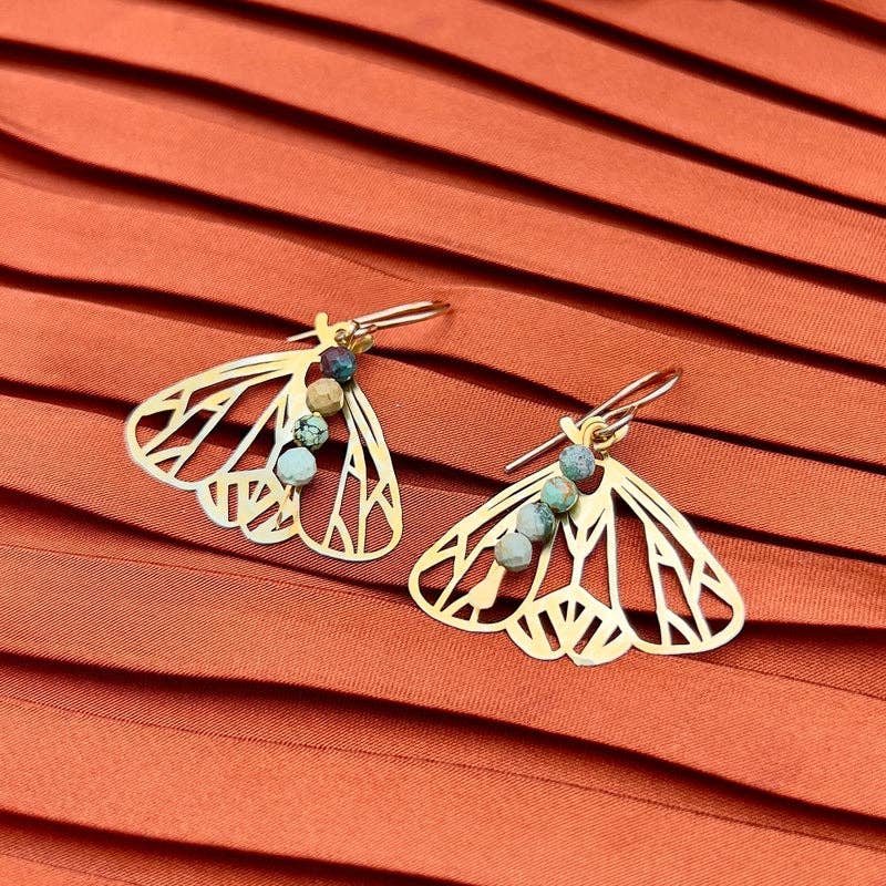 The Peppered Moth Earrings (Small) by Fluff Hardware are handcrafted gold earrings featuring a raw brass moth pendant accented with turquoise beads. Finished with hypoallergenic 14k gold filled ear wires, these nature-inspired earrings offer lightweight movement and a subtle pop of color—an easy everyday accessory and a meaningful gift for anyone drawn to symbolic, artisan-made jewelry.