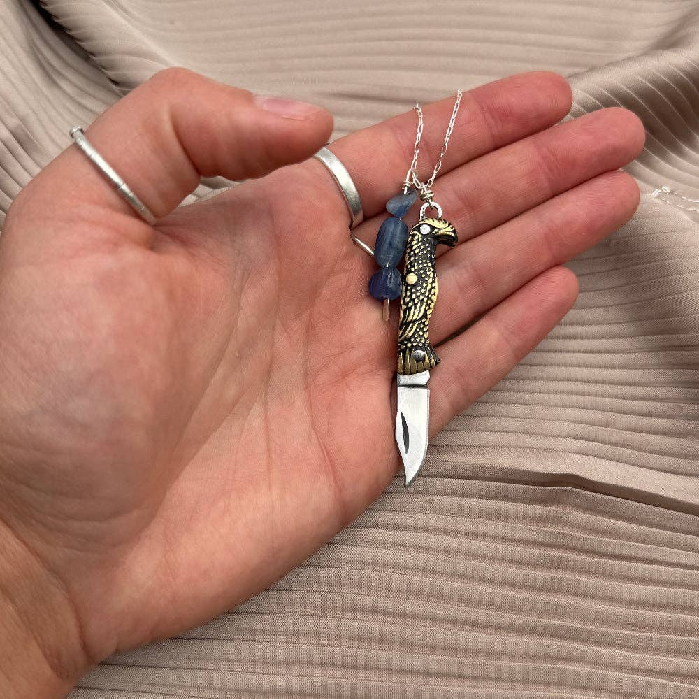 The Talon Necklace by Fluff Hardware is a handcrafted gold-filled necklace featuring an eagle-inspired functional talon utility charm accented with natural kyanite beads. Designed for intentional wear, this mixed-use piece blends symbolic jewelry with practical design. Finished with a hypoallergenic 14k gold filled chain, it’s a bold, meaningful accessory for those drawn to empowered, purpose-driven adornment.