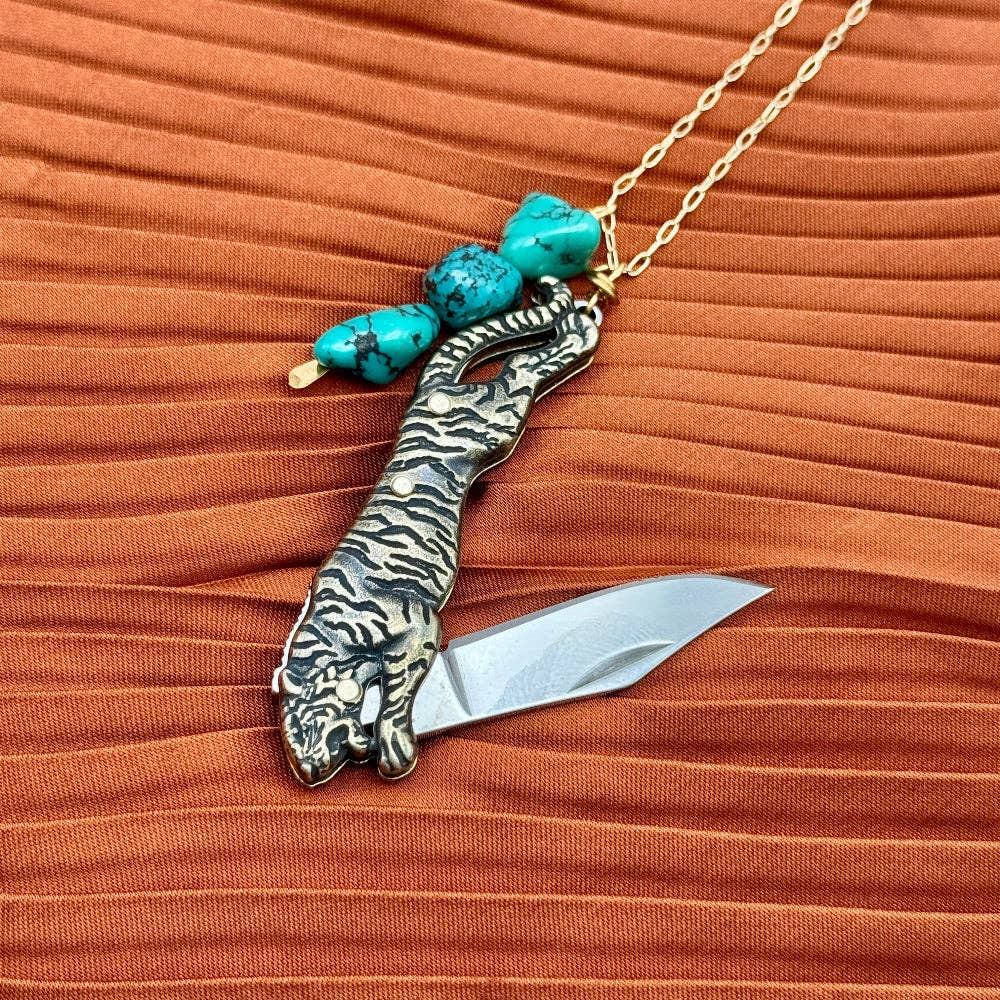 The Untamed Necklace by Fluff Hardware is a handcrafted gold-filled necklace featuring a tiger-inspired functional utility charm accented with natural turquoise nugget beads. Designed for empowered, intentional wear, this small-batch piece blends symbolic jewelry with practical design. Finished on a hypoallergenic 14k gold filled chain, it’s a striking accessory for those drawn to bold craftsmanship and purpose-driven adornment.