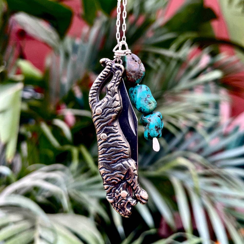 The Untamed Necklace by Fluff Hardware is a handcrafted gold-filled necklace featuring a tiger-inspired functional utility charm accented with natural turquoise nugget beads. Designed for empowered, intentional wear, this small-batch piece blends symbolic jewelry with practical design. Finished on a hypoallergenic 14k gold filled chain, it’s a striking accessory for those drawn to bold craftsmanship and purpose-driven adornment.