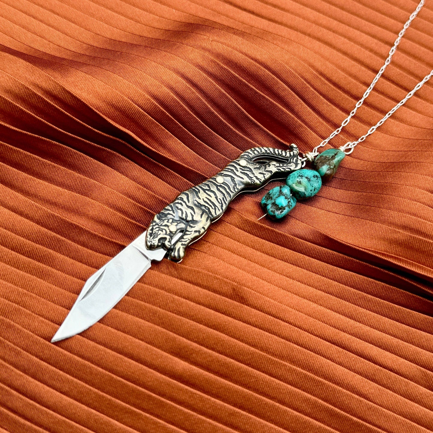 The Untamed Necklace by Fluff Hardware is a handcrafted gold-filled necklace featuring a tiger-inspired functional utility charm accented with natural turquoise nugget beads. Designed for empowered, intentional wear, this small-batch piece blends symbolic jewelry with practical design. Finished on a hypoallergenic 14k gold filled chain, it’s a striking accessory for those drawn to bold craftsmanship and purpose-driven adornment.