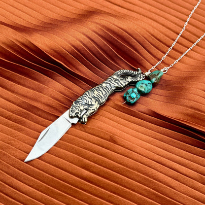 The Untamed Necklace by Fluff Hardware is a handcrafted gold-filled necklace featuring a tiger-inspired functional utility charm accented with natural turquoise nugget beads. Designed for empowered, intentional wear, this small-batch piece blends symbolic jewelry with practical design. Finished on a hypoallergenic 14k gold filled chain, it’s a striking accessory for those drawn to bold craftsmanship and purpose-driven adornment.