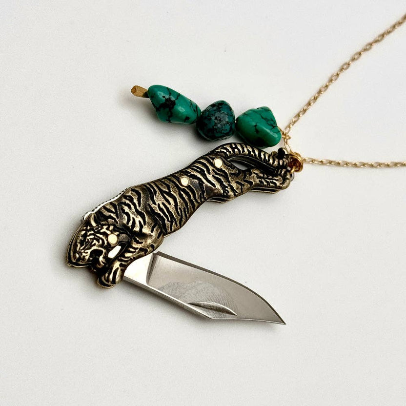 The Untamed Necklace by Fluff Hardware is a handcrafted gold-filled necklace featuring a tiger-inspired functional utility charm accented with natural turquoise nugget beads. Designed for empowered, intentional wear, this small-batch piece blends symbolic jewelry with practical design. Finished on a hypoallergenic 14k gold filled chain, it’s a striking accessory for those drawn to bold craftsmanship and purpose-driven adornment.