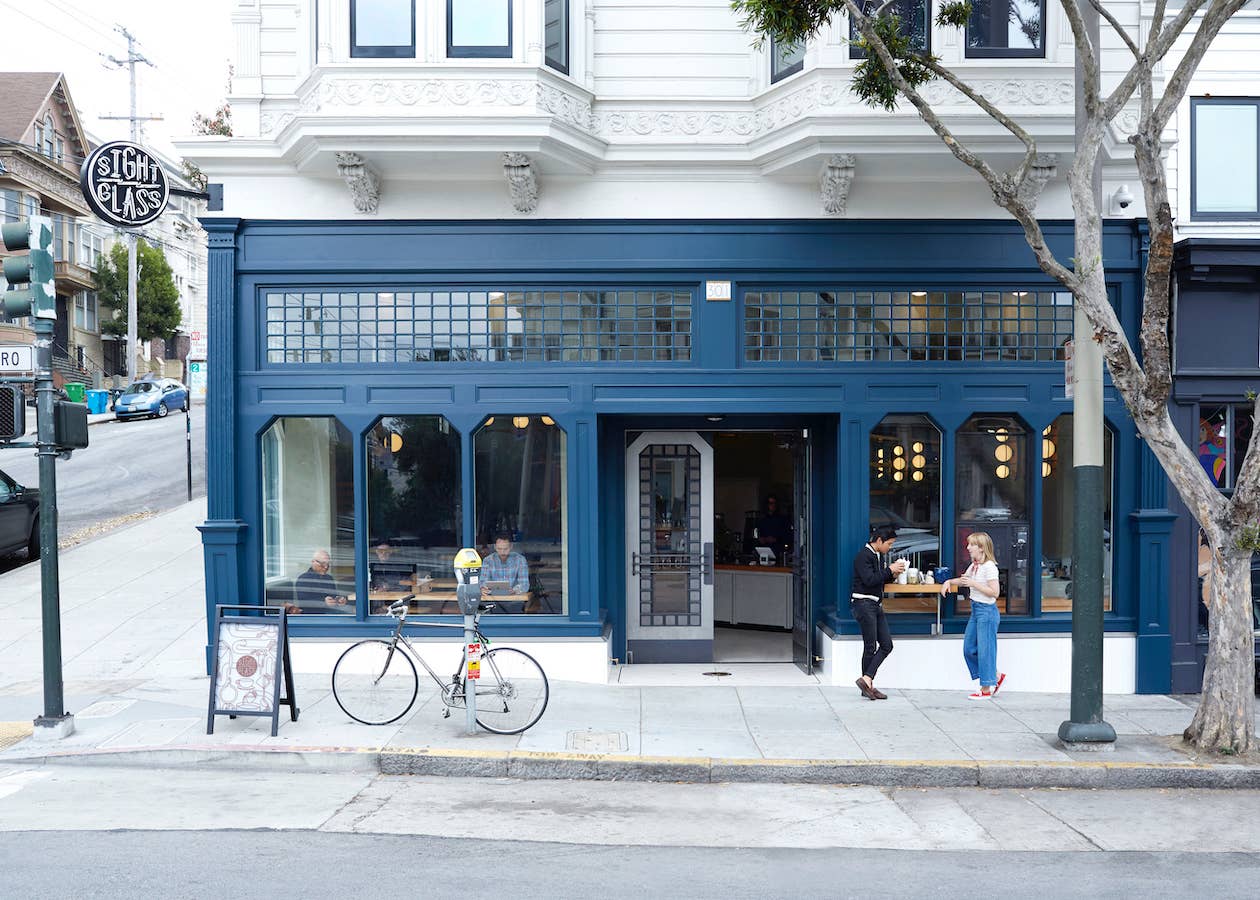Street view of the Sightglass Coffee café in San Francisco with the blue storefront and customers enjoying coffee.