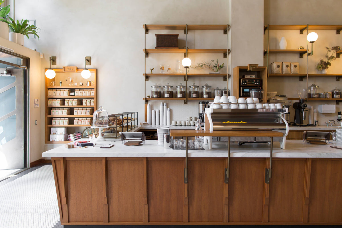Interior of the Sightglass Coffee café with espresso bar, coffee bags, and open wood shelving.