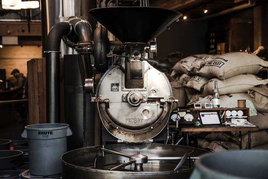 Large Probat coffee roaster at the Sightglass Coffee roastery beside bags of green coffee beans ready for roasting.