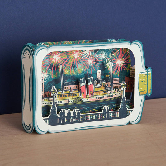 Tom Jay Fireworks Spectacular die-cut greeting card featuring a paddle steamer beneath colorful fireworks inside a bottle-shaped design.