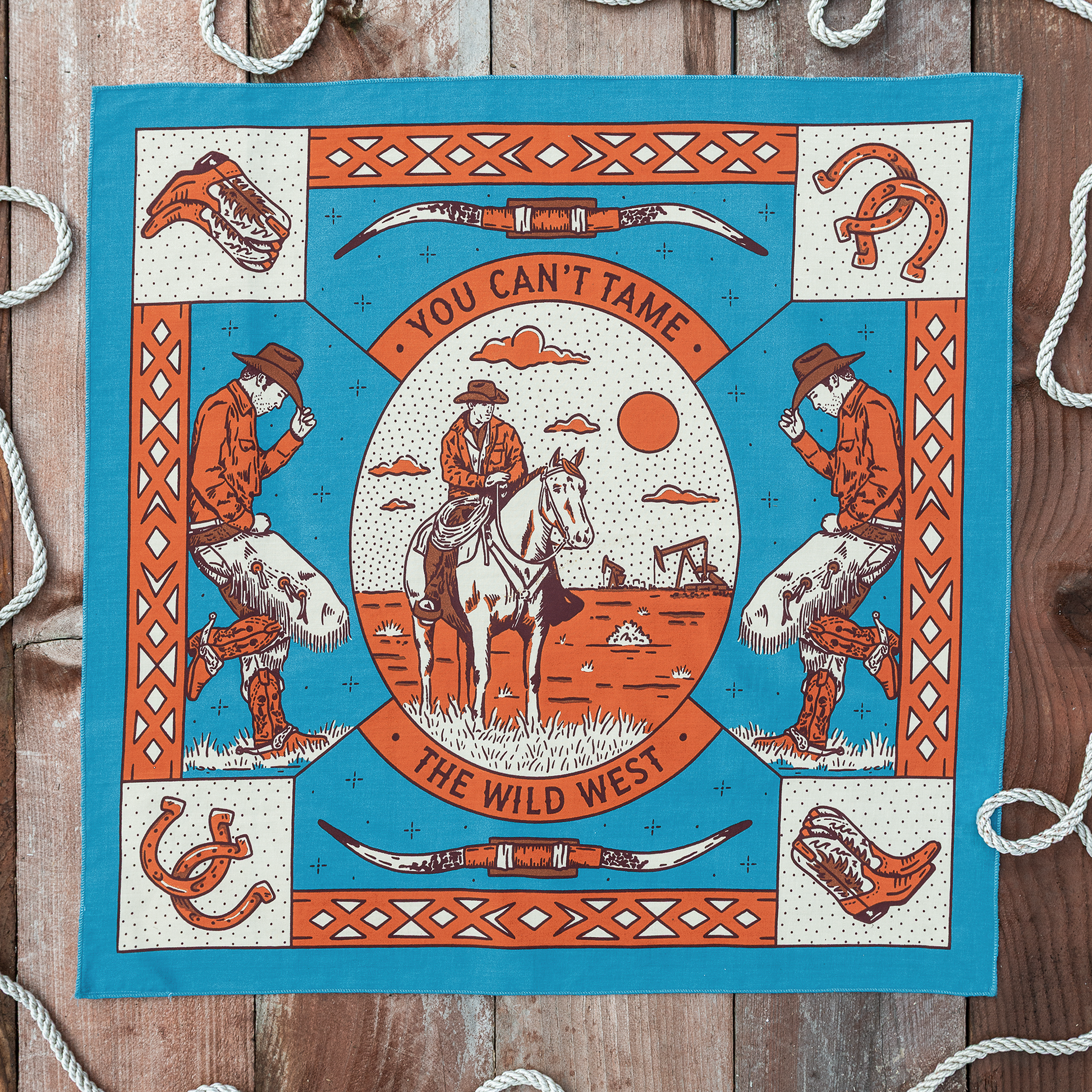 Van Berkemeyer Wild West bandana featuring a cowboy on horseback surrounded by longhorn skulls, horseshoes, cowboy boots, and bold Western-inspired illustrations.